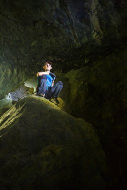 Büyük kayanın üzerinde oturan genç çocuk