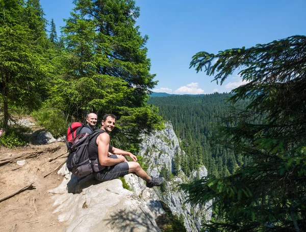 Wandelaars zittend op de rand van een zeer hoge klif — Stockfoto