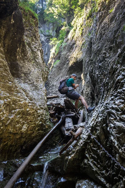 Backpacker άνθρωπος που πηγαίνει κάτω σε ένα gorgehiker στέκεται μέσα σε μια μεγάλη σπηλιά — Φωτογραφία Αρχείου