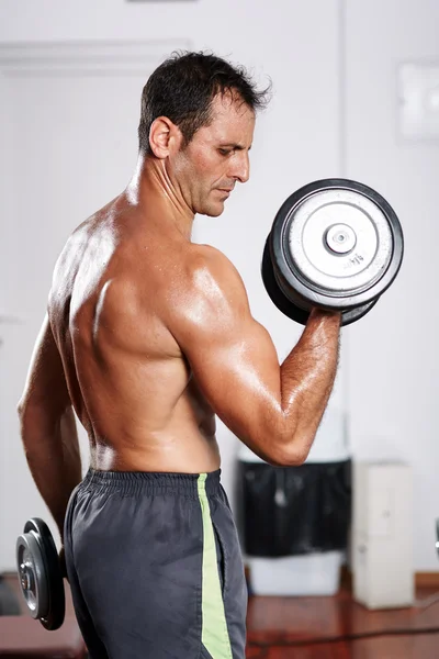 Člověk dělá biceps curl v tělocvičně — Stock fotografie