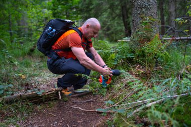 Apuseni Dağları 'ndaki yosunlu patika boyunca orman bitkilerinin detaylarını fotoğraflayan bir adam.