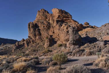 Teide Ulusal Parkı 'ndaki Roques de Garcia' da geniş engebeli kaya oluşumu açık mavi gökyüzünün altında Tenerife 'de popüler bir yürüyüş yolu boyunca fotoğraflandı.