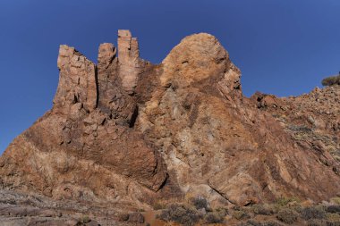 Teide Ulusal Parkı 'ndaki Roques de Garcia' da geniş engebeli kaya oluşumu açık mavi gökyüzünün altında Tenerife 'de popüler bir yürüyüş yolu boyunca fotoğraflandı.