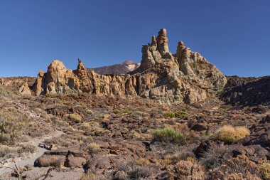Teide Dağı, Tenerife 'deki Tenerife Ulusal Parkı' nda açık mavi bir gökyüzünün altında görülebilen Roques de Garcia volkanik oluşumları ve güneşli kuleler.