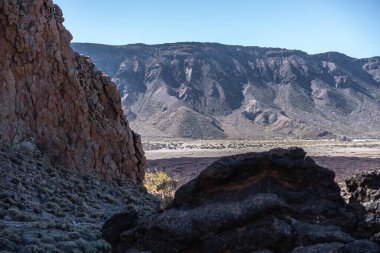 Tenerife 'deki Teide Ulusal Parkı' nda sertleştirilmiş pahoehoe lav yüzeyinin dalgalı dokularını ve katılaşmış akış şekillerini yakından görürüz.
