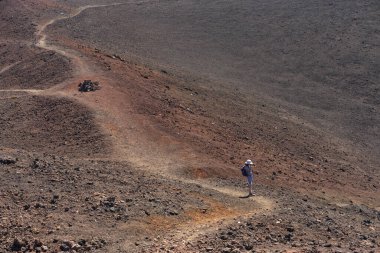 Kadın yürüyüşçü Samara yakınlarında parlak güneş ışığı altında volkanik bir araziyi fotoğraflıyor.