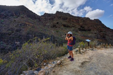 Kadın fotoğrafçı, dramatik volkanik kanyon duvarlarını Barranco del Infierno yolu boyunca bir bakış açısıyla yakalıyor.