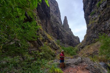 Dişi yürüyüşçü, yüksek volkanik kayalıklara ve Barranco del Infierno 'nun dramatik dar vadisindeki kaya zirvesine bakıyor.