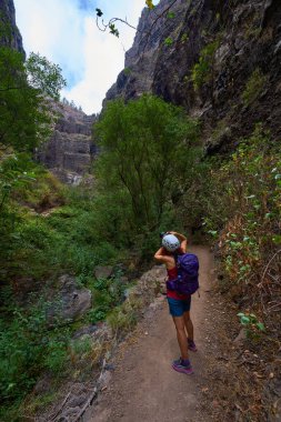 Kadın fotoğrafçı, Barranco del Infierno 'nun dar vadisindeki yüksek katmanlı volkanik kayalıkların görüntülerini yakalıyor.