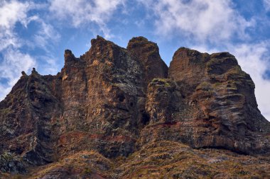 Engebeli volkanik kitle gösterileri jeolojik katmanları ortaya çıkardı, çok seyrek bitki örtüsüyle noktalandı..