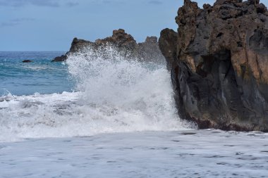 Şiddetli okyanus Tenerife kıyı şeridi ile kesişirken köpüklü beyaz köpüklü bazalt kıyıları kaplıyor..