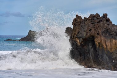 Şiddetli okyanus Tenerife kıyı şeridi ile kesişirken köpüklü beyaz köpüklü bazalt kıyıları kaplıyor..