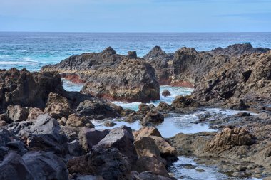 Tenerife Kanarya Adaları 'ndaki El Bollullo sahilinde gelgit havuzları ve okyanus suyuyla volkanik kaya oluşumları.
