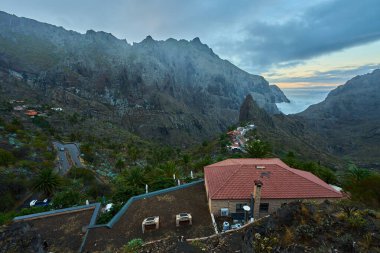 Dar bir tepeye tünemiş olan Masca 'nın tarihi köyü bazalt duvarlar ve yumuşak sabah buharı tarafından çerçevelenmiştir..