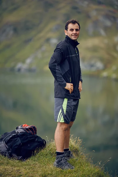 Турист отдыхает у горного озера Стоковая Картинка