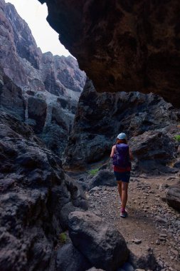 Bir yürüyüşçü Masca geçidinde yürüyor, profesyonel kamera ekipmanları ve temel güvenlik teçhizatı taşıyor.