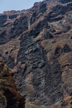 Katmanlı erozyon desenleri olan pürüzlü volkanik lav kaya yüzeyinin detaylı dokusu Masca geçidinde