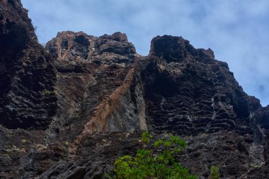 Gündüz vakti birden fazla volkanik mağara açıkları ve dik Masca geçidi uçurum duvarındaki aşınma şekilleri seyrek bitki örtüsüyle birlikte görülüyor.