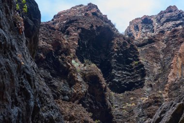 Çoklu volkanik mağara açıkları ve dik Masca geçidi uçurum duvarında seyrek bitki örtüsüyle erozyon desenleri.