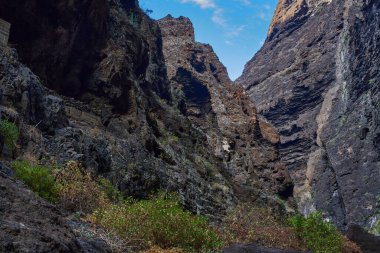 Karanlık mağaranın içinden, yamaçlarda bitki örtüsüyle açılan Masca vadisi uçurum oluşumlarının görüntüsü