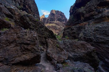 Doğal mağaralar ve bitki örtüsünün yer aldığı bazalt kayalıkların tabanındaki dar patikalar.