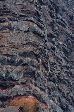 Kıyı şeridi boyunca renkli kaya katmanları ve volkanik dokuların makro görünümü