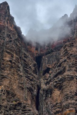 Turuncu ve koyu renkli kayalıklar Kanarya Adaları 'ndaki Atlantik Okyanusu' nun üzerinde yükseliyor.
