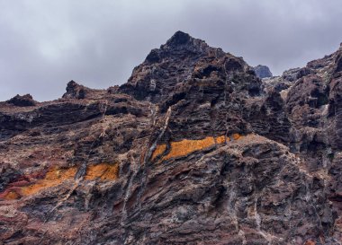 Los Gigantes kayalıklarından görülen turuncu ve kahverengi katmanlı renkli volkanik kaya oluşumlarının detaylı görüntüsü