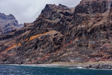 Tenerife 'deki Atlantik Okyanusu' ndan yükselen katmanlı erozyon desenleri ve bitki örtüsü olan Los Gigantes volkanik kayalıkları.