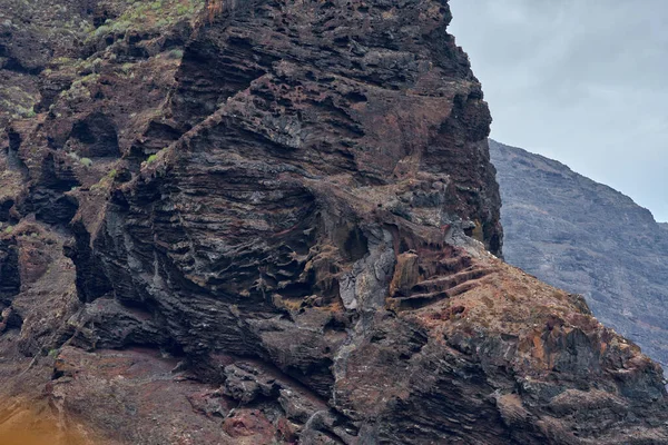 Turuncu ve koyu renkli kayalıklar Kanarya Adaları 'ndaki Atlantik Okyanusu' nun üzerinde yükseliyor.