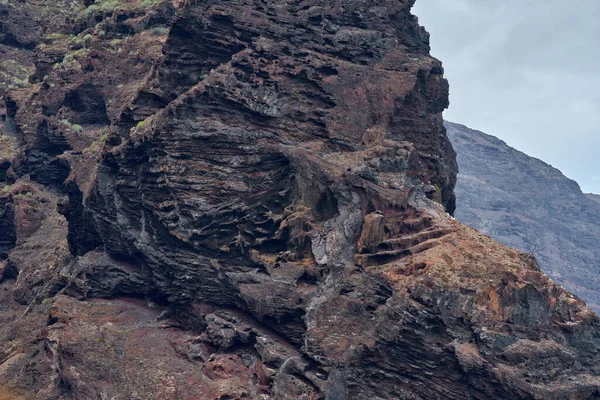 Turuncu ve koyu renkli kayalıklar Kanarya Adaları 'ndaki Atlantik Okyanusu' nun üzerinde yükseliyor.