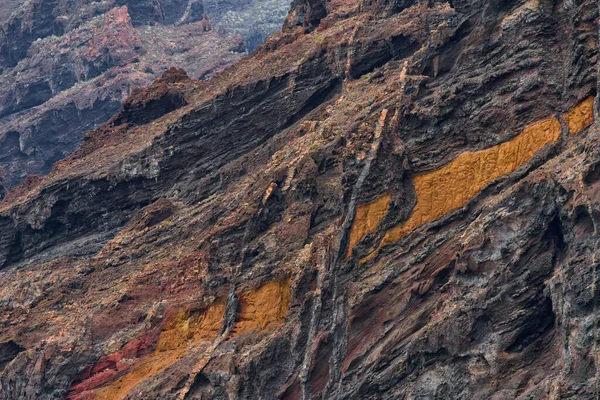 Los Gigantes kayalıklarından görülen turuncu ve kahverengi katmanlı renkli volkanik kaya oluşumlarının detaylı görüntüsü