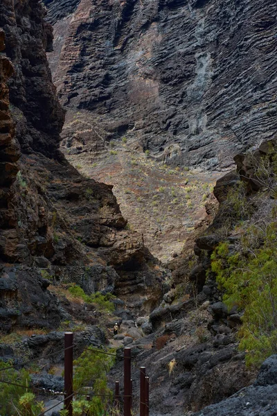 Dar Masca geçidi, yüksek volkanik kaya duvarları ve küçük akarsu arasında tahta direklerle yürüyüş yolu.