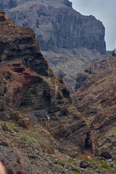 Katmanlı kaya oluşumları mağaralar ve Los Gigantes kayalıklarında seyrek bitki örtüsüyle aşınmış volkanik vadi.