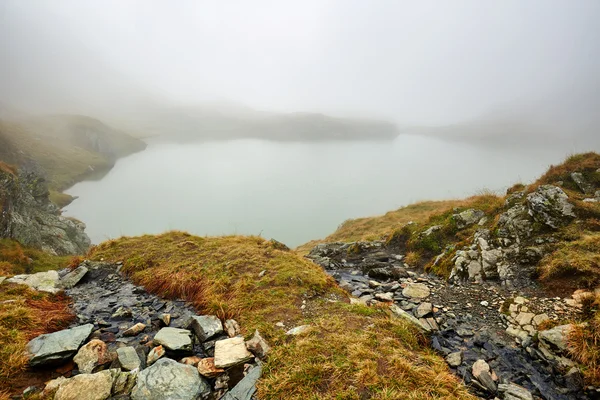 Lago en la niebla entre montañas — Foto de Stock