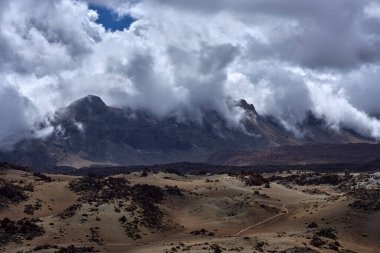 Guajara Dağı volkanik sünger taşı tepecikleri ve Las Kanada Caldera zemininin lav sahalarının üzerinde dönen alçak bulutların arasından çarpıcı bir şekilde yükselir.