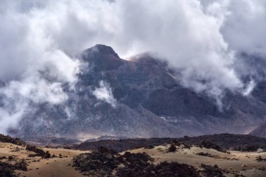 Guajara Dağı volkanik sünger taşı tepecikleri ve Las Kanada Caldera zemininin lav sahalarının üzerinde dönen alçak bulutların arasından çarpıcı bir şekilde yükselir.