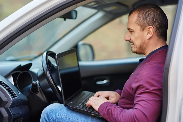 Empresário trabalhando em um laptop no carro — Fotografia de Stock