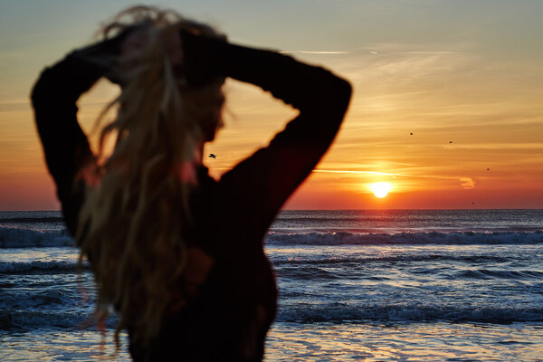 Женщина на пляже на восходе солнца
