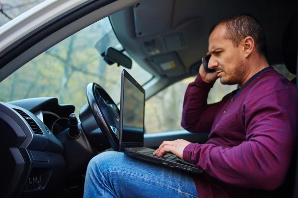 Zakenman die op een laptop in de auto werkt — Stockfoto