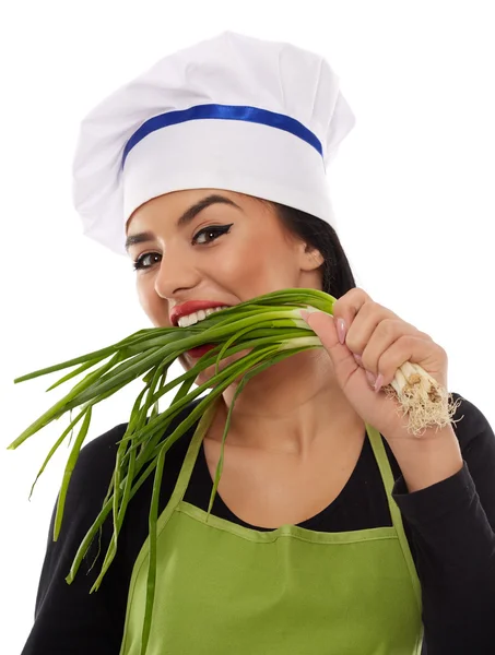 Mulher cozinheiro mordendo cebolinhas — Fotografia de Stock
