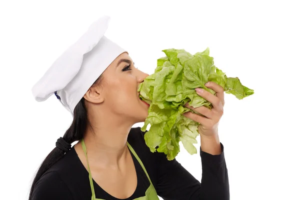 Woman cook biting lettuce — Stock Photo, Image