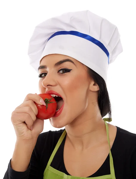 Mulher cozinheiro comer um tomate fresco — Fotografia de Stock