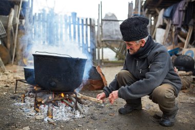 İhtiyar ateşe odun koyarak