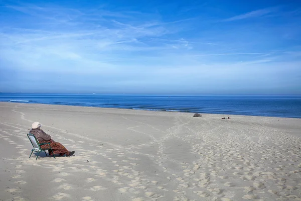 Mujer sentada en silla en la costa del mar — Foto de Stock