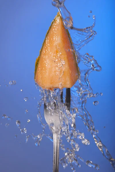 Melão fruta cantaloupe garfo azul fundo splash — Fotografia de Stock