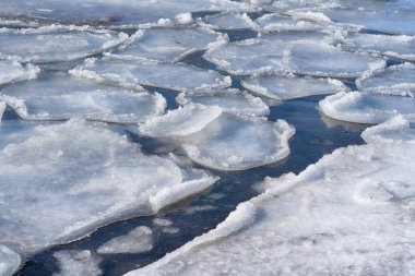 Donmuş bir körfezin yüzeyinde eriyen buzla birlikte bahar arkaplanı. Donmuş bir gölün karlı kıyısı.