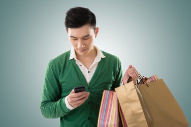 alışveriş torbaları tutarak ve cep telefonu kullanarak