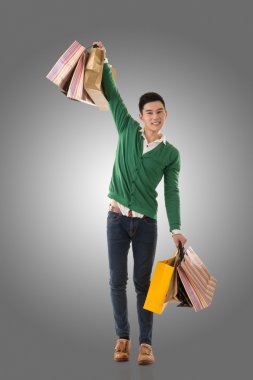 Asya genç adam alışveriş torbaları holding