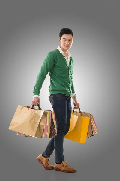 Asian young man holding shopping bags — Stock Photo, Image